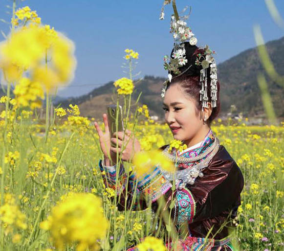 トン族の村に春來たる、花と戯むる村の女性たち