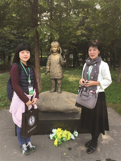 バウヒニアの花を持つ少女の像の前に立つ佐々木真理子さんと古谷恵莉子さん。