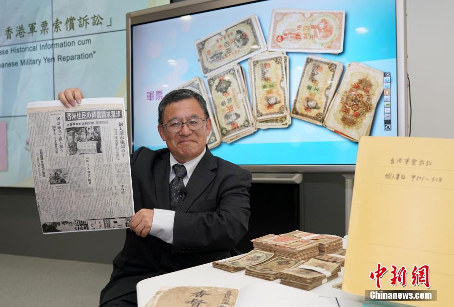 「香港軍票訴訟」関連の歴史資料を見せる和仁廉夫氏 (撮影?張■、■は火へんに韋)。