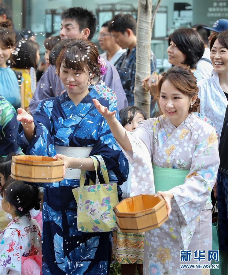 東京?銀座のイベント會場となった通りで、浴衣姿で打ち水をする女性（撮影?杜瀟逸）。