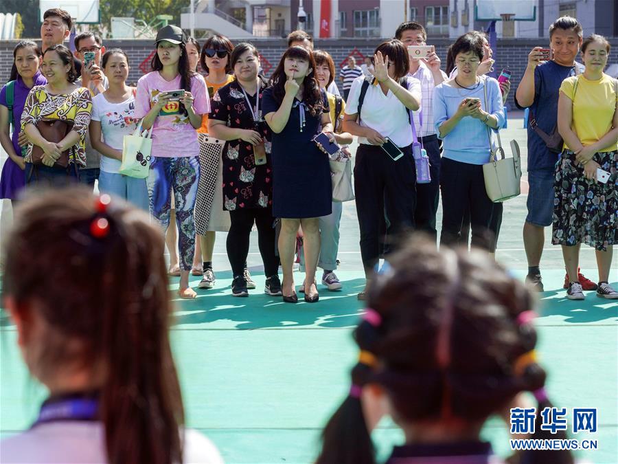 9月1日、北京市東城區(qū)燈市口小學?燈市口キャンパスで行われた入學式終了後の記念撮影をする新一年生の橫で寫真を撮る保護者ら。中には、子供にポーズのとりかたを教える保護者の姿も (撮影?沈伯韓)。