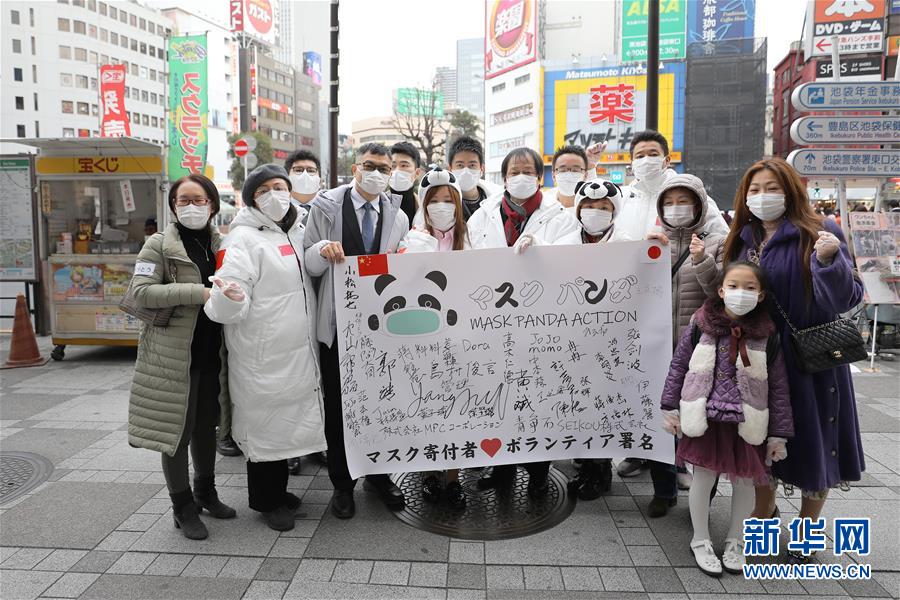 2月29日、日本の東京?池袋駅前で道行く人々にマスクを配った後記念撮影し、中國と日本の感染拡大防止にエールを送る「マスクパンダアクション」のボランティアたち（撮影?杜瀟逸）。