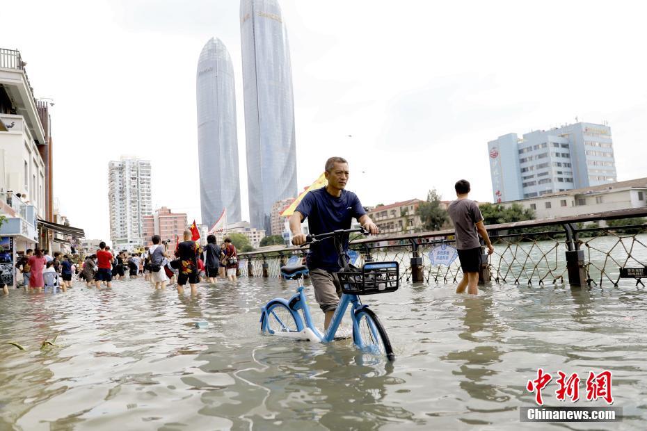 潮位が上昇して冠水した沙坡尾歩道を自転車を押しながら移動(dòng)する市民（撮影?李思源）。