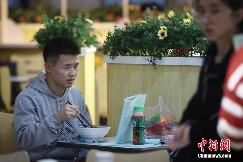 麺料理を食べながらも復習を続ける學生（撮影?泱波）。