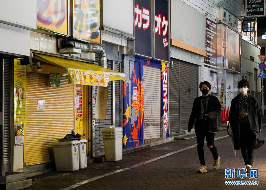 5月7日、店のシャッターが閉まり閑散とした商店街を歩く男性。