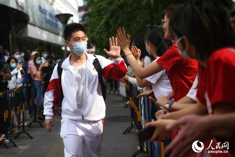 6月7日、北京人民大學(xué)附屬中學(xué)（中高一貫校）の入口で、順序良く試験會(huì)場(chǎng)に入る受験生とハイタッチを交わす見(jiàn)送りの人々（撮影?翁奇羽）。