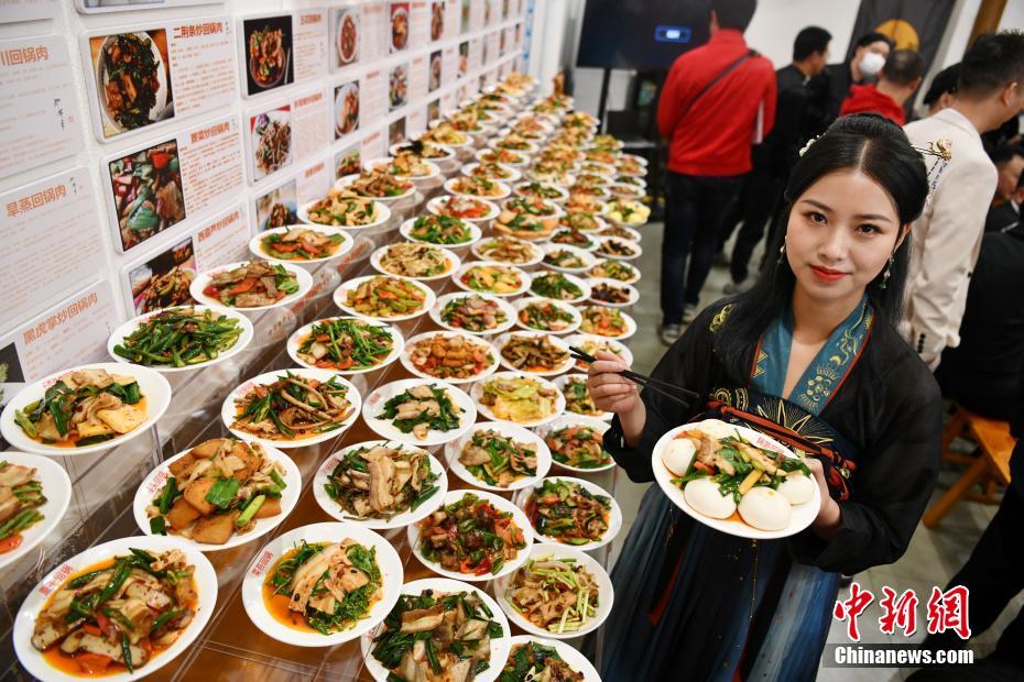 自らが作った「ニンニクの芽回鍋肉」を見せる、「108種類の回鍋肉メニュー」を企畫した羅程丹さん（撮影?張浪）。