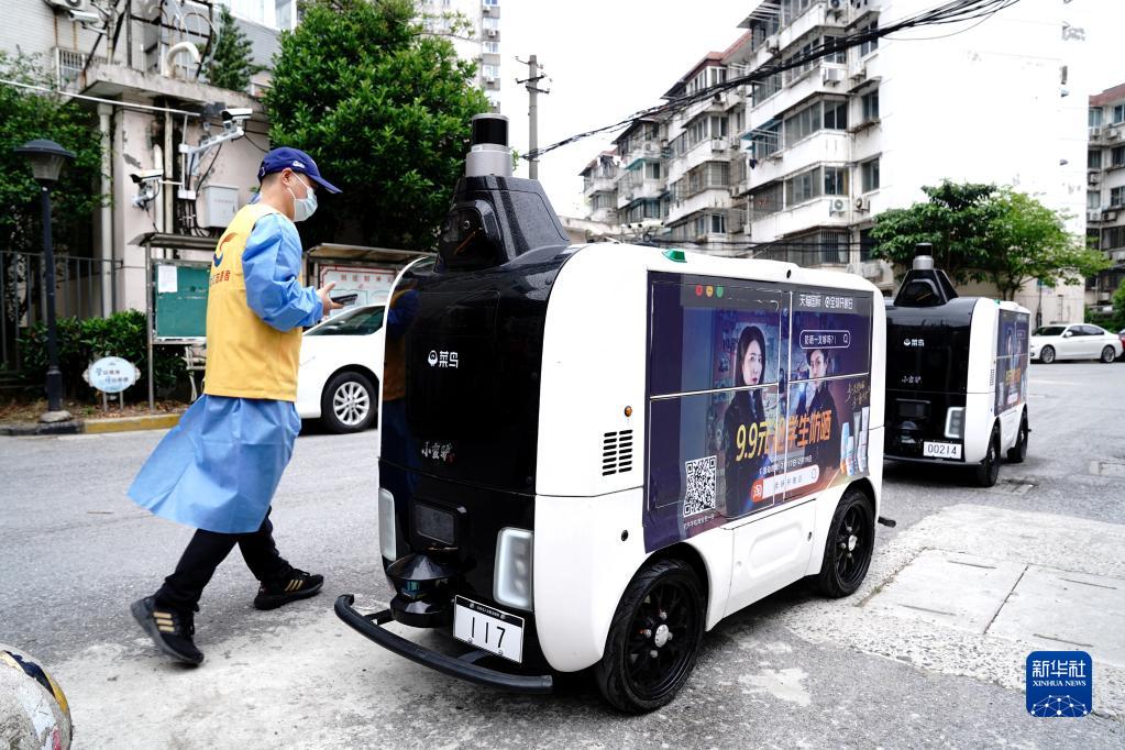 4月25日、コミュニティ入口で配送物を無(wú)人配送車に入れる上海市楊浦區(qū)長(zhǎng)海路街道（エリア）浣紗小區(qū)（コミュニティ）の黨員ボランティア（撮影?張建松）。