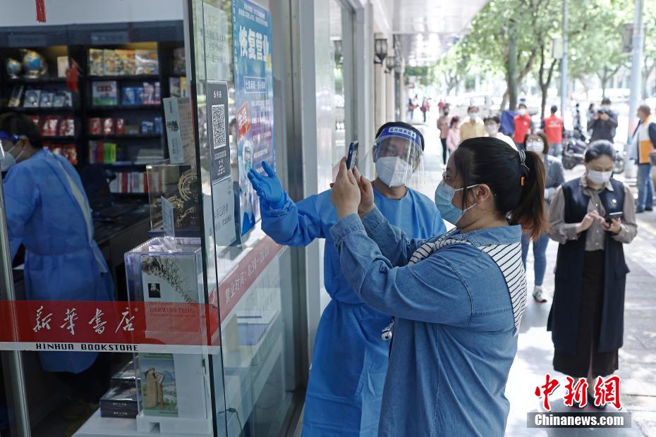 新華書店金山朱涇店で、入口で「場所コード」の登録スキャンを行った後、店內に入る買物客（撮影?殷立勤）。