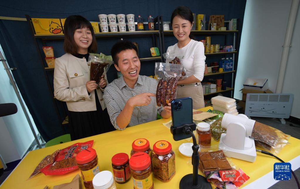 貴州省順義市綏陽県農産物流通センターで、ライブコマースを通じてソーセージを販売する蔣栄慶さん（寫真中）とスタッフ（6月12日撮影?楊楹）。