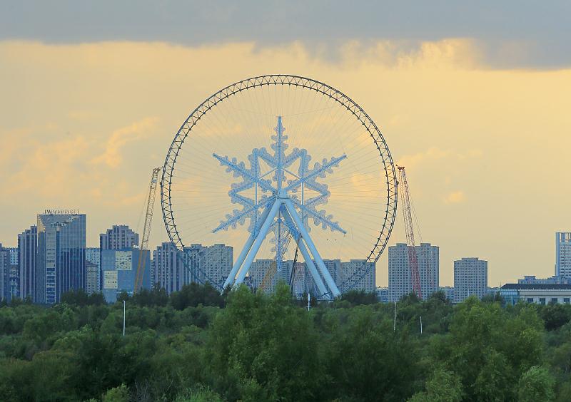 8月24日、黒竜江省哈爾浜（ハルビン）氷雪大世界で、建設中の観覧車の「雪の結晶」取り付け工事がこのほど完了、松花江のほとりに巨大な雪の結晶が出現。（寫真著作権はCFP視覚中國が所有のため転載禁止）