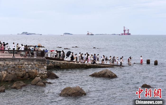 「海に続く線路」の寫真を撮るために列を作って待つ観光客。（撮影?曲正揚）