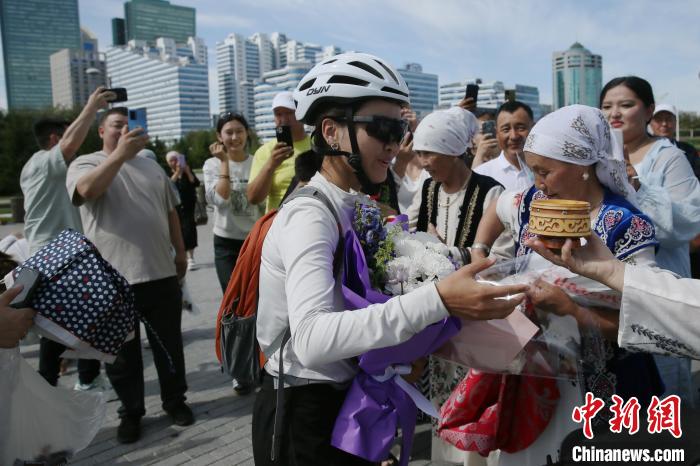 布爾蓮さんは新疆維吾爾（ウイグル）自治區烏魯木斉（ウルムチ）を自転車で出発して25日後の現地時間今月13日に、2000キロ以上離れたアスタナに到著。寫真は現地の華人?華僑の大歓迎を受ける布爾蓮さん（撮影?単璐）。