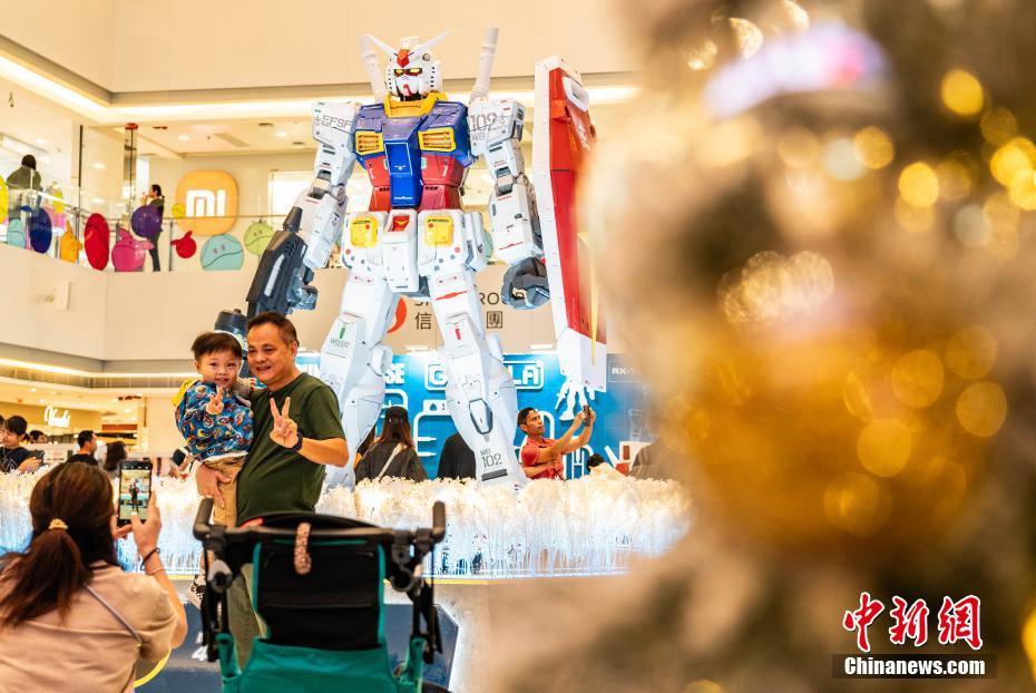 高さ3メートルの初代ガンダムRX-78-2の立像の前で記念撮影する市民や観光客（撮影?侯宇）。